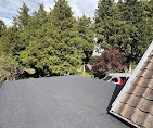 New flat roof covering next to a tiled roof